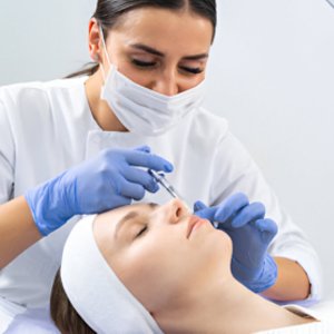 Clinician giving a facial injection while the patient lies down