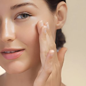 Woman applying cream to her cheek